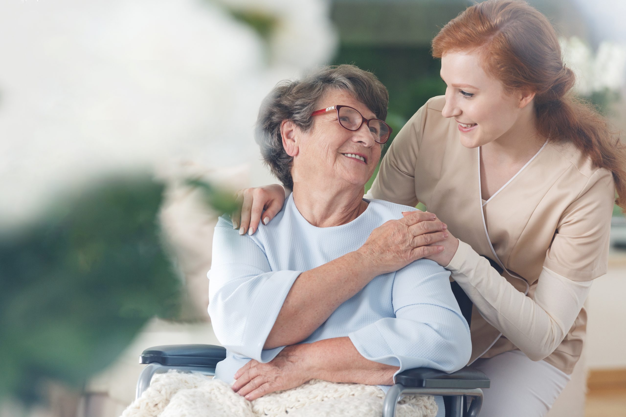 Pflegerin liest einem älteren Paar in gemütlicher Umgebung vor – Fokus auf persönliche Betreuung mit Zeit