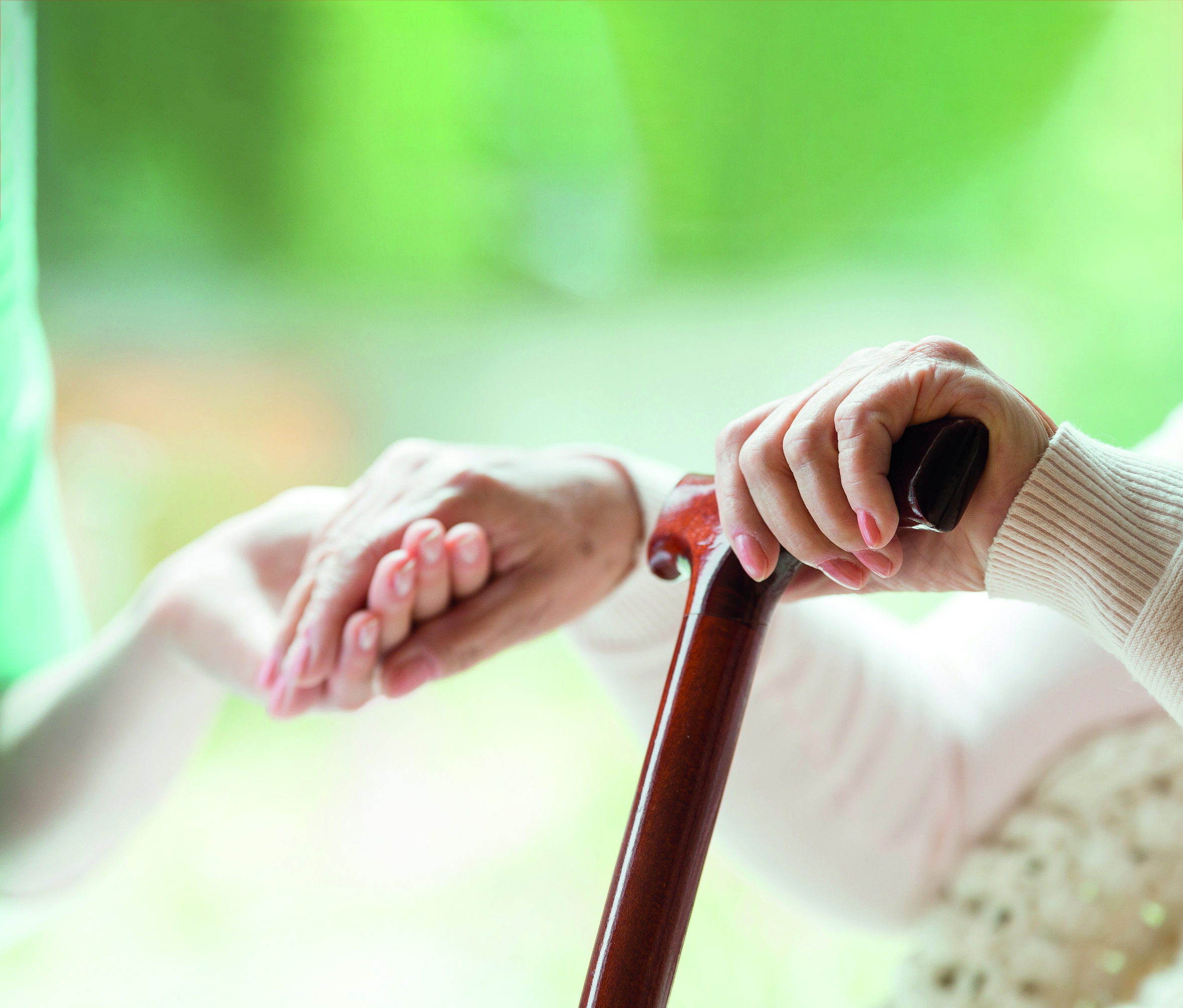 Elder person supported on wooden stick during rehabilitation in friendly hospital